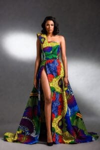 Bold Black woman in a vibrant multicolored asymmetrical high-slit Ankara gown with dramatic leg slit, fashion-forward African print style