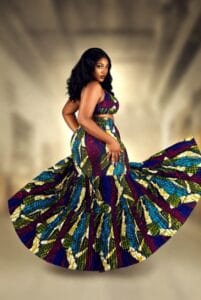 Curvy Black woman wearing vibrant pleated and tiered Ankara skirt with matching crop top, showing beautiful volume and movement