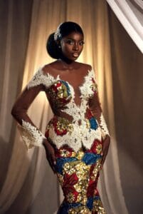 Elegant Black woman in a luxurious Ankara and white lace combination mermaid gown with sheer lace sleeves, premium Aso Ebi style