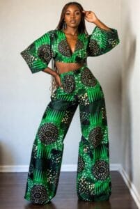 Stylish Black woman wearing trendy green and black Ankara crop top with flowing palazzo pants, dynamic fashion pose